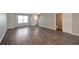 Living room featuring wood-look flooring, neutral walls, a white door and open floorplan to the kitchen at 402 Whippet St, Union City, GA 30291