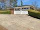 A two car garage in a single-story brick home featuring clean, white garage doors and manicured green bushes at 6691 Birch Dr, Winston, GA 30187