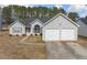 Traditional home featuring a two-car garage and a cozy, landscaped front yard on a sunny day at 4768 Score Ct, Snellville, GA 30039