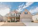 Lovely two-story brick home showcasing a covered front porch and a spacious two-car garage at 879 Tranquil Way, Hampton, GA 30228