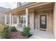 Cozy front porch featuring brick columns, black shutters, and decorative 'HOME' sign at 879 Tranquil Way, Hampton, GA 30228