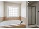 Bathroom with a tub, tiled surround, and glass-enclosed shower at 140 Ryan Ln, Covington, GA 30014