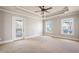 Spacious main bedroom boasts tray ceilings, a ceiling fan, plush carpet and backyard views at 140 Ryan Ln, Covington, GA 30014