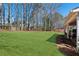 Expansive backyard featuring lush green grass, mature trees, and a covered patio area at 2688 Stockbridge Way, Dacula, GA 30019