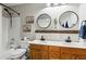 Renovated bathroom featuring double vanity, round mirrors, and shower with white subway tile at 2688 Stockbridge Way, Dacula, GA 30019
