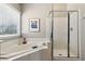 Bright main bathroom with a soaking tub, glass shower, and a large window at 2688 Stockbridge Way, Dacula, GA 30019