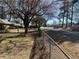 A street view of a property featuring a fence, mature trees, and houses along the road at 496 Elizabeth Sw Ln, Mableton, GA 30126