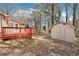 View of the backyard, featuring a wooden deck and storage shed, surrounded by trees and foliage at 2090 Walden Park, Snellville, GA 30078