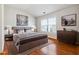 Bedroom with a queen-size bed, wooden floors, two windows, and two pieces of art at 4550 Cold Spring Ct, Cumming, GA 30041