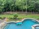 Aerial view of a backyard showcasing an in-ground pool with a tanning ledge and wooded area at 8760 Colonial Pl, Duluth, GA 30097