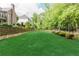 Beautifully landscaped backyard featuring a retaining wall, lush lawn, and surrounding trees at 8760 Colonial Pl, Duluth, GA 30097