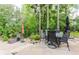 Backyard patio with outdoor seating, surrounded by lush trees, offers a tranquil retreat at 8760 Colonial Pl, Duluth, GA 30097
