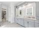 A sleek bathroom features dual sinks with illuminated mirrors and elegant gray cabinetry at 8760 Colonial Pl, Duluth, GA 30097
