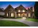 Beautiful brick and stone home with manicured lawn and inviting curb appeal at twilight at 8760 Colonial Pl, Duluth, GA 30097