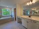 Bright bathroom featuring a soaking tub under a window and a vanity with a large mirror at 3677 Thornhill Ct, Douglasville, GA 30135