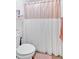 Neutral bathroom with a shower featuring a decorative pink and white shower curtain, and a white toilet at 138 Lakestone Pkwy, Woodstock, GA 30188