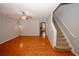An open-concept living room features hardwood floors, a ceiling fan, and access to a staircase and other rooms at 1290 Adcox Sq, Stone Mountain, GA 30088