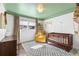This cute Bedroom features a sage ceiling, a wooden crib, and a comfy chair at 1300 Valley Ct, Roswell, GA 30075