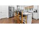 Well-lit kitchen featuring stainless steel appliances, a marble-topped island with barstool seating, and wooden floors at 1300 Valley Ct, Roswell, GA 30075