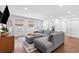 Bright living room with a comfortable grey sectional, wood floors, and natural light from the windows at 1300 Valley Ct, Roswell, GA 30075