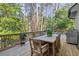 Exterior shot of the back deck featuring a wooden dining table, a grill, and a view of the wooded yard at 160 Wing Mill Rd, Sandy Springs, GA 30350