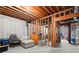 Unfinished basement area featuring concrete walls, exposed wood beams, and a chair with a chest of drawers at 160 Wing Mill Rd, Sandy Springs, GA 30350