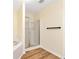 Bathroom featuring a glass shower stall, tub with tile surround and wood-look flooring at 386 Creek Manor Way, Suwanee, GA 30024