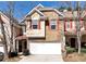 Charming townhome showcasing a brick facade, complemented by a one-car garage and well-maintained landscaping at 386 Creek Manor Way, Suwanee, GA 30024