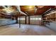Unfinished basement features concrete flooring and two garage doors with exposed wood ceiling rafters and duct work at 98 Pace Dr, Hiram, GA 30141