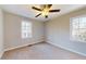 A bright bedroom with neutral walls, carpeted floors, two windows, and a ceiling fan at 98 Pace Dr, Hiram, GA 30141