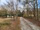Long, leaf-strewn driveway lined with trees and glimpses of the charming home creates a woodsy welcome at 1619 Flowery Branch Rd, Auburn, GA 30011