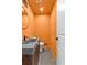 Stylish powder room with orange walls, a modern sink, and a round mirror at 260 Sandy Lake Cir, Fayetteville, GA 30214
