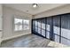 Well-lit bedroom with a large window, gray wood floors, and modern blue closet doors at 3540 Paddocks Pkwy, Suwanee, GA 30024
