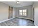 Empty bedroom featuring stylish wood-look flooring, one large window, and neutral walls at 3540 Paddocks Pkwy, Suwanee, GA 30024