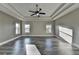 Spacious main bedroom featuring tray ceilings, ceiling fan and hardwood floors with large windows to bring in lots of sunlight at 3540 Paddocks Pkwy, Suwanee, GA 30024