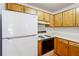 Efficient kitchen boasts wood cabinets and a white refrigerator at 135 Wilbanks Dr, Fayetteville, GA 30215