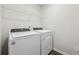 Modern laundry room featuring a white washer and dryer set and wire shelving for organized storage at 1705 Trout Lily Pl, Smyrna, GA 30126