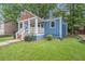 Charming blue home boasts a welcoming front porch, green lawn, and mature trees for ample shade at 125 Warren Ne St, Atlanta, GA 30317