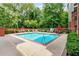 Community swimming pool surrounded by lush greenery, lounge chairs, and orange umbrellas at 50 Biscayne Nw Dr # 6117, Atlanta, GA 30309