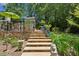 Beautiful backyard with stone steps leading to a patio area with a bright green umbrella and lush landscaping at 750 Crest Valley Nw Dr, Sandy Springs, GA 30327