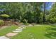 Expansive backyard featuring lush green lawn, stone pathways, and mature trees, perfect for outdoor enjoyment at 750 Crest Valley Nw Dr, Sandy Springs, GA 30327