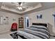 Bedroom featuring tray ceiling, carpeted floor, stylish area rug, and a red modern chair at 1211 Chapel Estates Way, Dacula, GA 30019