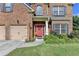 Close-up view of a two-story brick home's front door, attached garage, and landscaped front yard at 1211 Chapel Estates Way, Dacula, GA 30019