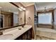 Stylish bathroom features a large mirror, double sink vanity, soaking tub, and tiled floors at 1211 Chapel Estates Way, Dacula, GA 30019