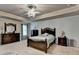 This is a carpeted main bedroom featuring a bed, dresser and stylish ceiling fan with light fixture at 1211 Chapel Estates Way, Dacula, GA 30019