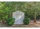 A small shed in the backyard surrounded by green grass and bushes at 320 Creekside Trl, Covington, GA 30016