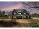 Charming two-story home with a covered porch, green siding, and a welcoming red front door at dusk at 529 Claude Scott Rd, Canton, GA 30115