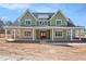 Inviting two-story home boasts a covered front porch, green siding, and white trim details under a bright blue sky at 529 Claude Scott Rd, Canton, GA 30115