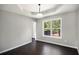 Bright dining room with a tray ceiling, hardwood floors, natural light, and an open doorway to the adjacent room at 221 Makayla Way, Temple, GA 30179