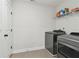 A laundry room featuring a washer, dryer, storage shelf, and white door at 871 Dunning St, Marietta, GA 30060